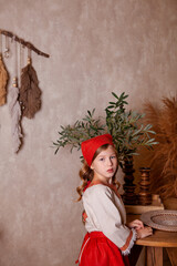 Wall Mural - little girl in a light linen shirt and a red scarf in a rustic style