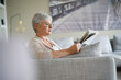 © goodluz - Senior woman reading newspaper, relaxed in sofa