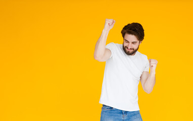 Laughing young bearded man posing isolated on yellow orange background studio portrait. People emotions lifestyle concept. Mock up copy space. Standing on toes, spreading hands.