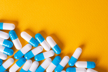 white and blue pills on yellow background