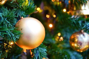 Golden smooth ball as decoration for New Years celebration, bokeh. Winter christmas tree in the snow with bauble, copy space