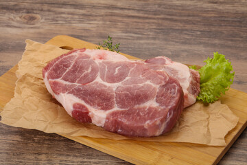 Raw pork steak over wooden board