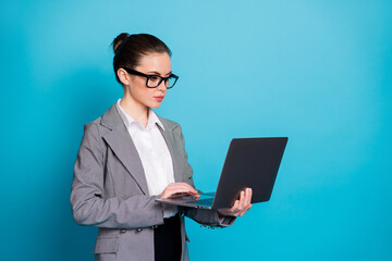 Canvas Print - Portrait of attractive focused lady geek IT expert holding in hands laptop working isolated over bright blue color background