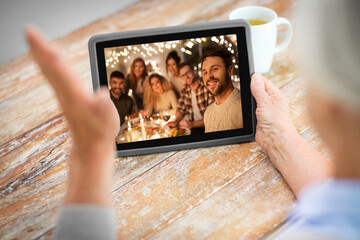 technology, communication and christmas holidays concept - senior woman having video call with her family on tablet computer at home