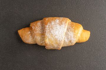 Bagel with powdered sugar. Butter sweet flour bakery product on a black background.