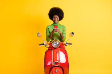 Sticker - Photo portrait of young brunette woman scooter rider holding red smartphone in two hands wearing casual clothes isolated on vivid yellow colored background