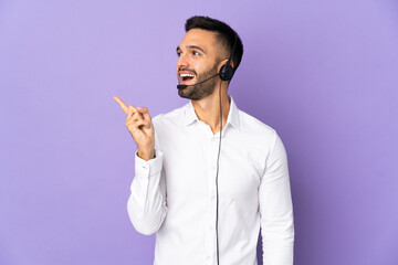 Telemarketer man working with a headset isolated on purple background intending to realizes the solution while lifting a finger up