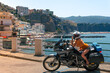 Young sexy girl posing. Motorcycle for tourism and travel. Wearing a helmet. In the background are views of the sea and hotels. Coast of Italy. Sunny day, vacation and trip.