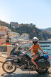 Young sexy girl posing. Motorcycle for tourism and travel. Wearing a helmet. In the background are views of the sea and hotels. Coast of Italy. Sunny day, vacation and trip. Vertical photo
