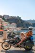 Young girl posing. Motorcycle for tourism and travel. Wearing a helmet. In the background are views of the sea and hotels. Coast of Italy. Sunny day, vacation and trip. Vertical photo