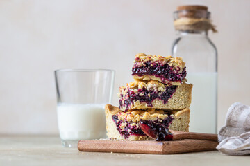 Wall Mural - Homemade berries jam shortcrust squares and glass of milk, light background. Selective focus.