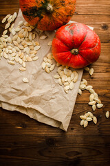 Pumpkin seeds, two pumpkins on craft paper and wooden background. Flatley. Top.