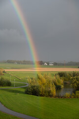 Wall Mural - A rainbow visible very close over the green fields in southern Sweden after a summer rain