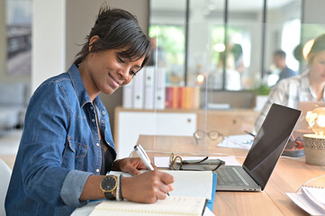 Office worker woman in open space area, protected by plexiglas