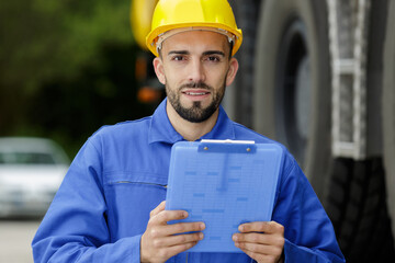 portrait of young mechanic wearing hardhat with clipboard