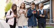 © VAKSMANV - Caucasian concentrated teens standing outdoors and typing on cellphones. Beautiful girl pupil browsing on smartphone near school. Young boy school student texting on mobile phone. Friends concept