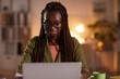 © Seventyfour - Front view portrait of young African-American woman using laptop while working in office or at home lit by cozy dim lighting, copy space