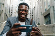 © Drobot Dean - Cheerful african american man using mobile phone and drinking coffee