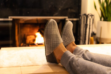 man in slippers relaxing with his feet up - warm cozy cabin scene with a fireplace in the background