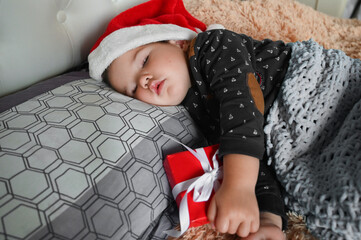 Wall Mural - Small red gift box in the hands of a sleeping boy. The joy of giving concept.