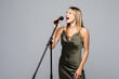© dianagrytsku - Beautiful young woman singing to microphone isolated on grey background