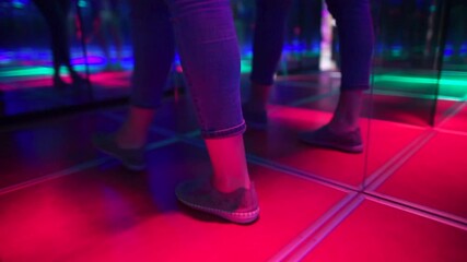 Feet of a visitor lost in a mirror maze in an amusement park. Finding a way out of a difficult confusing situation. Glowing floor tiles.