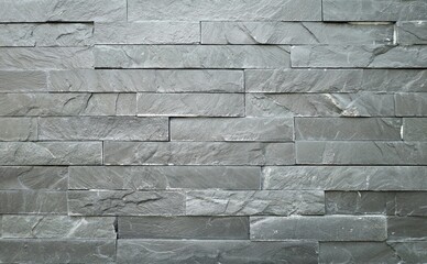 Stone wall cladding made of horizontal gray bricks of natural rock stacked . Background and texture