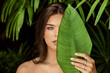 Beautiful brunette woman closeup with plants. Green, flower, emotion portrait natural beautiful big ey