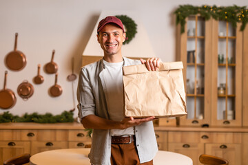 Canvas Print - a delivery man with a package of food stands in a Christmas interior