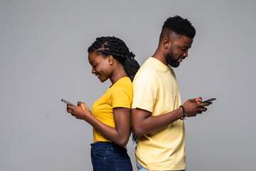 Portrait of young african couple with mobile phone spy each other on gray background