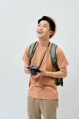 Portrait of cheerful young Asian tourist man holding digital camera and taking photo when standing over white background.