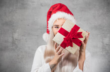 Santa Woman Holding Christmas Gifts Isolated On Gray Background. Happy Young Girl Wearing Red Santa Hat And Holding Present Box