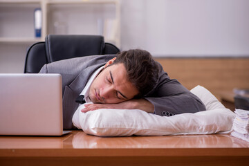 Young male employee sleeping at workplace