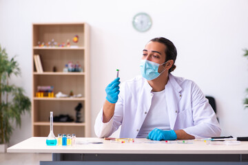 Young male chemist working in the lab during pandemic