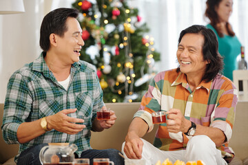 Poster - Happy middle-aged Asian men laughing when drinking tea at Christmas party