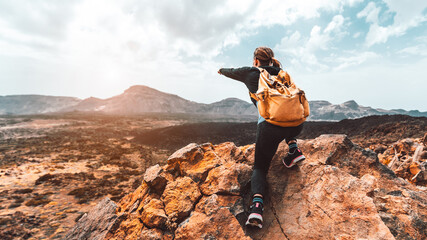 Wall Mural - beautiful hiker woman on the top of the mountain pointing at the sunset valley. girl with backpack t