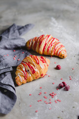 two fresh croissants on wooden board and cloth napkin