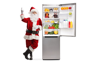 Canvas Print - Full length portrait of santa claus leaning on a fridge and pointing up