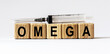 © Stanislau - Text OMEGA made from wooden cubes. White background