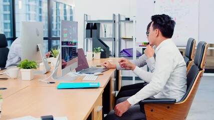 Wall Mural - Asian businessman discuss together in office, young coworkers work on laptop and desktop computer. Corporate business, financial consult, partnership teamwork, or information technology concept