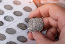 Numismatics. Old Collectible Coins Made Of Silver On A Wooden Table. A Collector Holds An Old Coin.