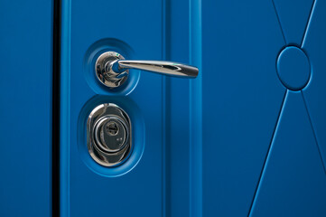 chrome handle in steel color in metal entrance door in blue color and modern finish