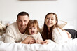 © jul14ka - Portrait of a young happy family lying in bed smiling and looking at the camera.