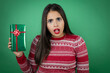 © Irene - Young beautiful girl holding gift over isolated white background afraid and shocked with surprise and amazed expression, fear and excited face.