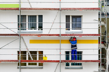 the worker performs finishing works in the renovation of the facade of an apartment house