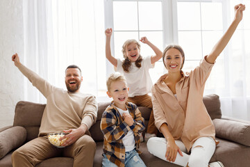 Wall Mural - Family celebrating goal on sofa.