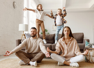 Happy parents  meditating in room with playful kids.