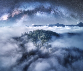 Wall Mural - milky way arch over the mountains in low clouds at starry night in summer. landscape with sky with s