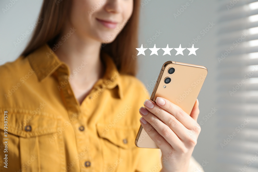 Woman leaving review online via smartphone indoors, closeup. Five stars over gadget - obrazy, fototapety, plakaty 