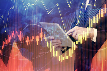 Double exposure of man's hands holding and using a digital device and forex graph drawing. Financial market concept.